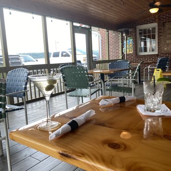 The Lost River Grill - Screened outdoor dining - A restaurant interior features a wooden ceiling, ceiling fans, and large windows with a view of parked cars outside. - American Near Me - Lost River, West Virginia