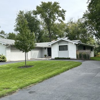 Prestigious Pavement - Prestigious Pavement repaired driveway - A white, single-story house with a garage and a driveway, set in a green yard with trees and shrubs. - Masonry/Concrete Near Me - Alsip, Illinois