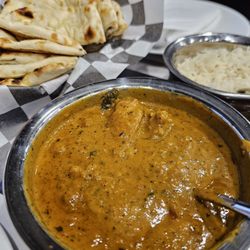 The Curry Lounge - Chicken Xacuti, chicken in a spicy sauce with coconut and poppy seeds. A Bread Basket in the background, with a variety of naan and kulcha.