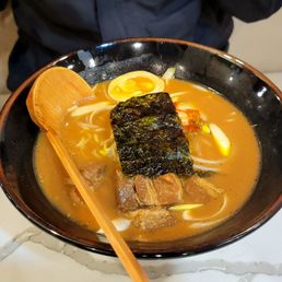 a bowl of ramen and a wooden spoon a bowl of ramen and a wooden spoon