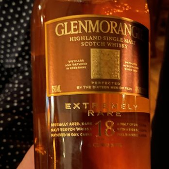 The Gamekeeper - a hand holding a bottle of whisky - New American Near Me - Boone, North Carolina
