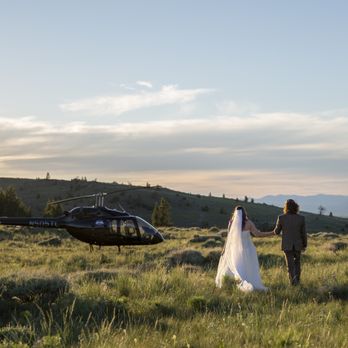 Scenic Vows - A couple walk hand in hand through a grassy meadow towards a helicopter - Event Photography Near Me Scenic Vows - A couple walk hand in hand through a grassy meadow towards a helicopter - Event Photography Near Me