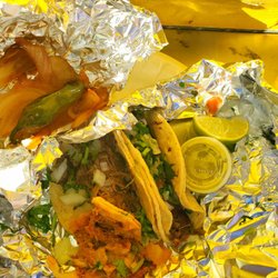 Two barbacoa and one deshebrada tacos along with complementary sautéed onion, roasted jalapeño and a small portion of charros.