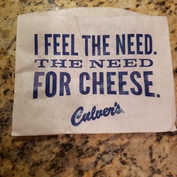 Culver's - A paper wrapper with the phrase "I feel the need. The need for cheese." printed in blue, placed on a speckled granite countertop. - Fast Food Near Me - Chicago, Illinois