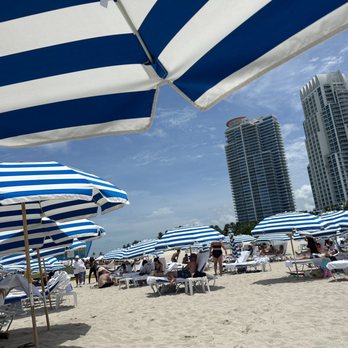 Bentley Beach Club - people sitting under blue and white umbrellas - Social Clubs Near Me - Miami Beach, Florida Bentley Beach Club - people sitting under blue and white umbrellas - Social Clubs Near Me - Miami Beach, Florida