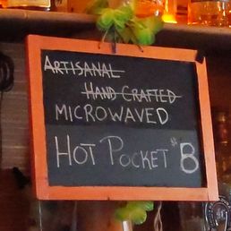 Penis! - A chalkboard menu sign displays handwritten text promoting artisanal, handmade, microwaveable hot pockets for $8.