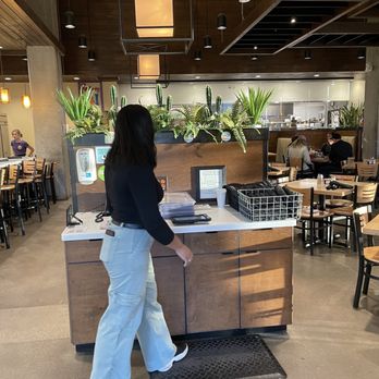 Urban Egg - Belleview - a woman standing at a counter - Breakfast & Brunch Near Me - Denver, Colorado