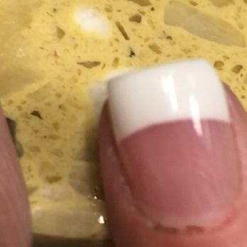JL Nails - Another bleeding cuticle. - A finger with a French manicure is pressed against a yellow, porous sponge, showing the nail and part of the finger. - Nail Salons Near Me - Howell, Michigan