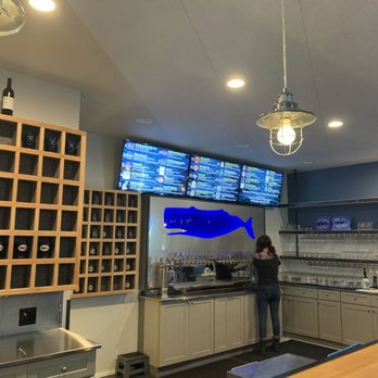 Tipsy Whale Mercantile - a woman standing in front of a tv - Wine Bars Near Me - Olympia, Washington Tipsy Whale Mercantile - a woman standing in front of a tv - Wine Bars Near Me - Olympia, Washington