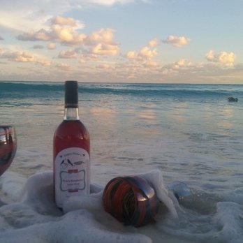 Empty Nester's Winery - a bottle of wine and two wine glasses on the beach - Wineries Near Me - Lecompton, Kansas