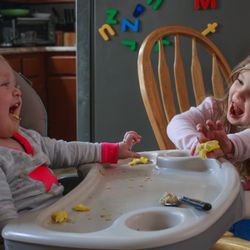 Lavon Photography - Two toddlers laughing heartily during a messy breakfast meal.