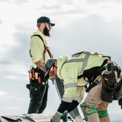 Moss Boss Roofing - Two roofing professionals working together on a residential roof installation.