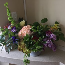 A truly spectacular staff created a special and fabulous/breathtaking floral arrangement!! The flowers brought my sister so much joy!! - A bouquet of mixed flowers including hydrangeas, snapdragons, and other blooms with green leaves in a gray vase, placed on a countertop.