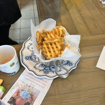 Windhill Pancake Parlor - Waffle fries are served in a small metal basket lined with paper, placed on a decorative plate on a wooden table. - Breakfast & Brunch Near Me - McHenry, Illinois