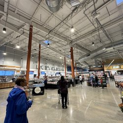 Whole Foods Market - Hot food bar stations area and coffee bar station.  3 tables with chairs near the window.