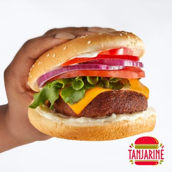 Tanjariné Kitchen - a hand holding a cheeseburger - Vegan Near Me Tanjariné Kitchen - a hand holding a cheeseburger - Vegan Near Me