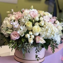 Flower Jazz - Soft and elegant hatbox arrangement with roses, hydrangea, spray roses, and seasonal blooms in blush, ivory, and white tones.