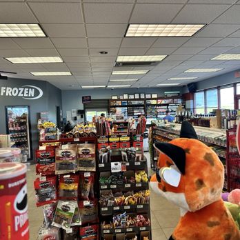Phillips 66 - Other side of store - Inside a convenience store, shelves are stocked with snacks, drinks, and other products. A plush toy is visible in the foreground near the right side. - Gas Stations Near Me - Casey, Illinois