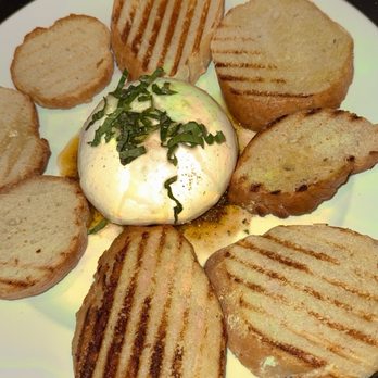 Zarletti - A plate features toasted bread slices arranged around a poached egg topped with chopped herbs, served on a white dish. - Italian Near Me - Milwaukee, Wisconsin