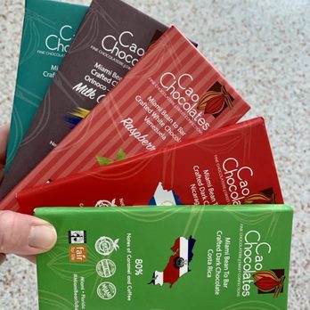 Cao Chocolates - a hand holding four chocolate bars - Food Delivery Services Near Me Cao Chocolates - a hand holding four chocolate bars - Food Delivery Services Near Me