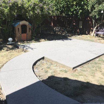 Valley Turf - a concrete patio with a dog house in the background - Masonry/Concrete Near Me