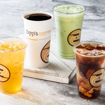 Ziggi's Coffee - Assortment of Ziggi's drinks on a marble surface: hot coffee, iced matcha, iced dark coffee, and a yellow iced tea drink. - Coffee & Tea Near Me - Frederick, Colorado Ziggi's Coffee - Assortment of Ziggi's drinks on a marble surface: hot coffee, iced matcha, iced dark coffee, and a yellow iced tea drink. - Coffee & Tea Near Me - Frederick, Colorado