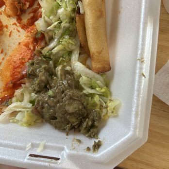 Si Senor - The guacamole was already brown when we got it home. - The image shows a foam takeout plate with shredded lettuce, a serving of guacamole, and a fried taquito. Part of a pizza with cheese and toppings is also visible on the plate. The plate is placed on a wooden surface, and a person's knee is partially visible at the bottom of the image. - Mexican Near Me - Deming, New Mexico