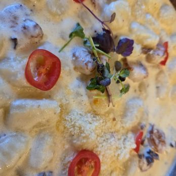 Fusionista - A creamy dish with visible chunks of ingredients, garnished with cherry tomato slices and microgreens, likely served at a fusion restaurant. - Peruvian Near Me - Montclair, New Jersey