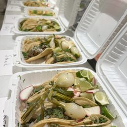a long table with tacos and other food items
