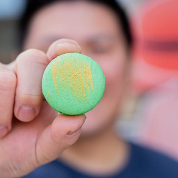 Joy Macarons - a person holding a green macaron - Macarons Near Me - Allen, Texas