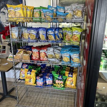 The Deli - Chip display - A multi-tiered metal rack holds different flavors of potato chips, including Deep River, Wise, and Ridges, in a convenience store setting. - Delis Near Me - Windsor Locks, Connecticut