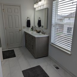 Installation of new tile, vanity, mirror, and lighting fixture, as well as paint.