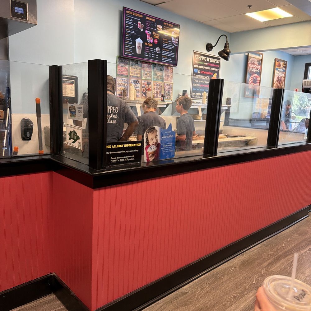 Three employees working on topping donuts. Three employees working on topping donuts.