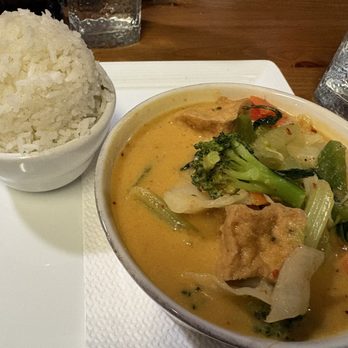Thai Table - Panang curry with tofu and extra veggies - A bowl of Thai curry with vegetables and tofu, accompanied by a bowl of white rice, on a white tray. - Thai Near Me - Topeka, Kansas