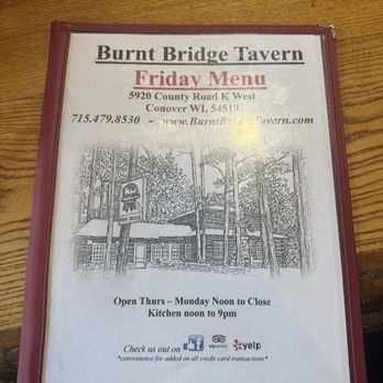 Burnt Bridge Tavern - Menu - The image features a laminated menu for Burnt Bridge Tavern, listing the Friday menu, address at 5920 County Road K West, Conover, WI, and contact information. The menu includes a sketch of the tavern building surrounded by trees, along with icons for Facebook, TripAdvisor, and Yelp. The opening hours are Thursday to Monday from noon to close, with kitchen hours from noon to 9 pm. - Bars Near Me - Conover, Wisconsin
