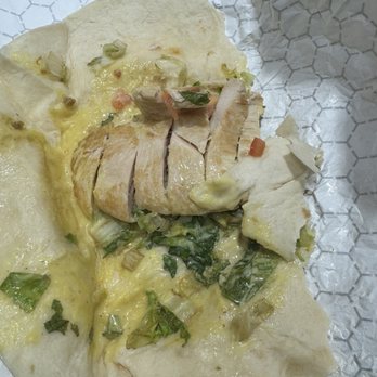 Friendly's - A chicken wrap with cheese, greens, and vegetables, partially eaten, on crumpled paper. - Ice Cream & Frozen Yogurt Near Me - Auburn, Massachusetts