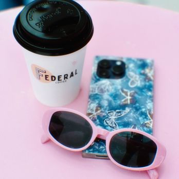 Federal Coffee - a cup of coffee and sunglasses on a pink table - Coffee & Tea Near Me - Los Angeles, California