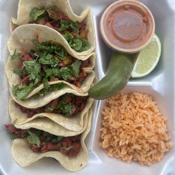 El Queretano - Al pastor tacos - A styrofoam food tray contains five tacos topped with chopped herbs, a portion of rice, a lime wedge, a jalapeño pepper, and a cup of sauce. - Food Trucks Near Me - Santa Fe, New Mexico