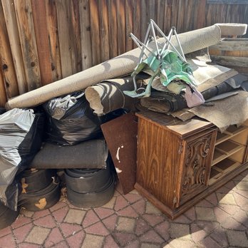Brown Rapid Junk Removal - Side yard construction debris and some household items including an old chest of drawers and two bikes. - Junk Removal & Hauling Near Me