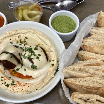 Pomella - Hummus Plate with Cheese-Stuffed Falafel, Harissa, Pickled Vegetables, Zhoug, and Pita - Middle Eastern Near Me - Oakland, California Pomella - Hummus Plate with Cheese-Stuffed Falafel, Harissa, Pickled Vegetables, Zhoug, and Pita - Middle Eastern Near Me - Oakland, California