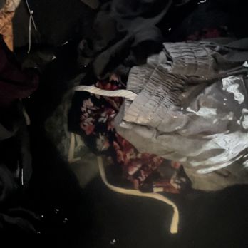606 Junk Removal - A collection of various clothing and fabric items, including pants and shirts, appears in a dark environment, possibly a laundry or storage area. - Junk Removal & Hauling Near Me - Chicago, Illinois
