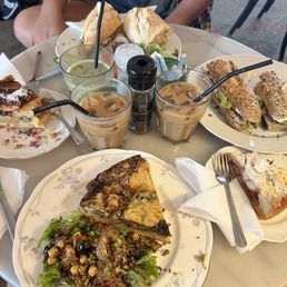 Quiche, tuna salad sandwich, goat cheese sandwich, an iced latte, vanilla latte, and matcha latte, strawberry crumble cake, and apple pie