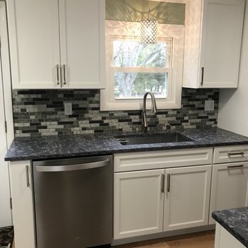 JC Contracting - a kitchen with white cabinets and black countertops - General Contractors Near Me JC Contracting - a kitchen with white cabinets and black countertops - General Contractors Near Me