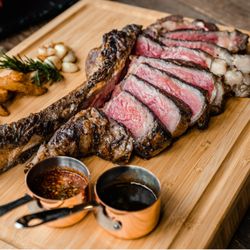 Wagyu tomahawk steak, sliced and served with sauces. Tomahawk steak, ribeye, grilled steak, steakhouse at home, premium beef.