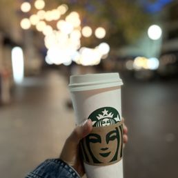 a person holding a starbucks cup a person holding a starbucks cup