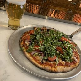 Vegan pizza topped with fresh arugula & tomato