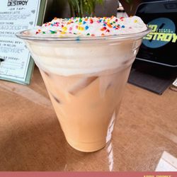 And Destroy Coffee & Gaming - Vanilla Latte with Oat Milk, topped with a vanilla cold foam and sprinkles.