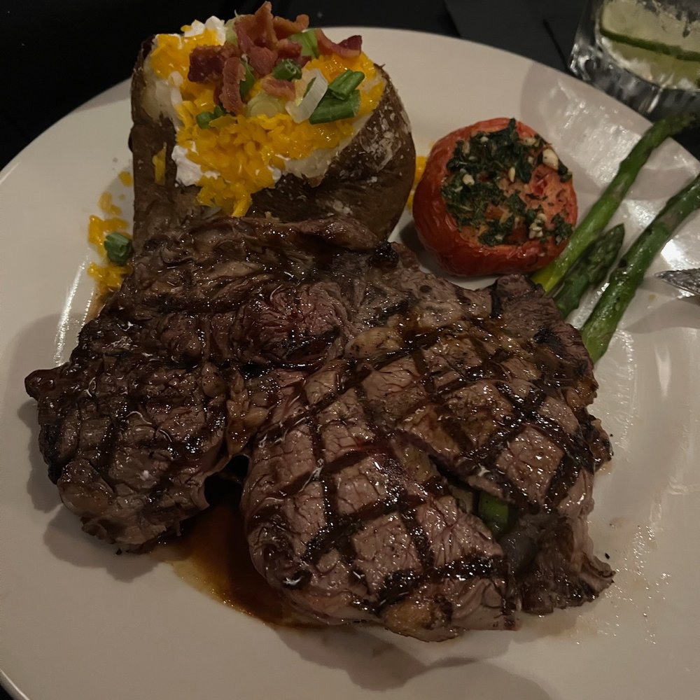 V's Steakhouse - 14oz boneless ribeye, baked potato, roasted tomato and asparagus. - Steakhouses Near Me - Mabank, Texas V's Steakhouse - 14oz boneless ribeye, baked potato, roasted tomato and asparagus. - Steakhouses Near Me - Mabank, Texas