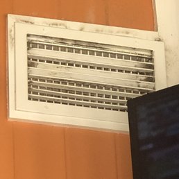 a dirty air duct in the corner of a room