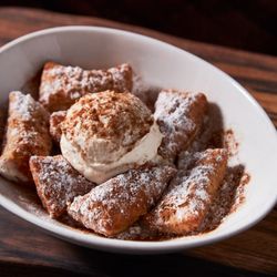 Boombozz Pizza & Watch Bar - Cinnamon-dusted poppers stacked and topped with rich cannoli cream and powdered sugar. A playful twist on a classic, made for sweet tooths